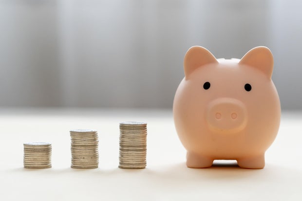 Piggy bank and stack of coins money on wooden background. Save money for prepare in future and pension retirement. Earning interest on savings. Growing your wealth and saving money concept