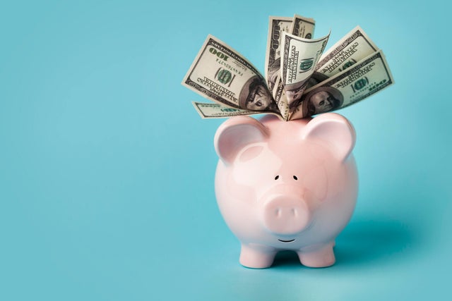 Pink piggybank stuffed with dollar bills 