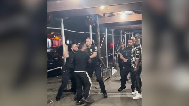 NYPD officers and individuals on a sidewalk 
