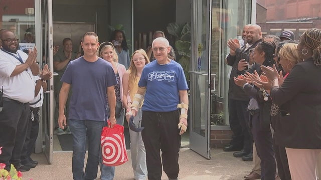 People clap as Officer Craig Romanczuk walks out of the hospital 