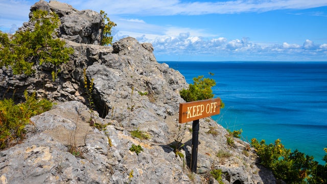 Rocky cliff on Mackinac Island with keep off sign 