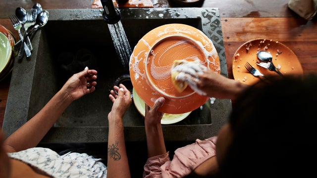 Mother and daughter washing plate in kitchen 