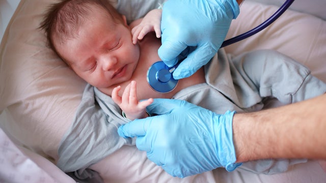 Doctor uses stethoscope to listen to baby 