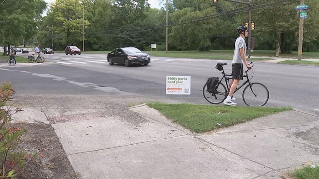 A cyclist waits to cross a busy street 