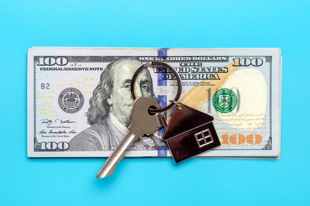 house or apartment key, dollars banknote isolated on blue background 