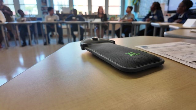 A cellphone locked in a pouch on a desk 
