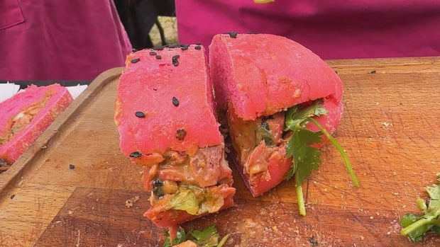 A sandwich on a pink roll at the Hoagie Throwdown event, the roll has black sesame seeds on top 