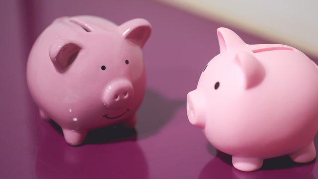 Two piggy banks on a purple wooden piece of furniture. Finance concept. 