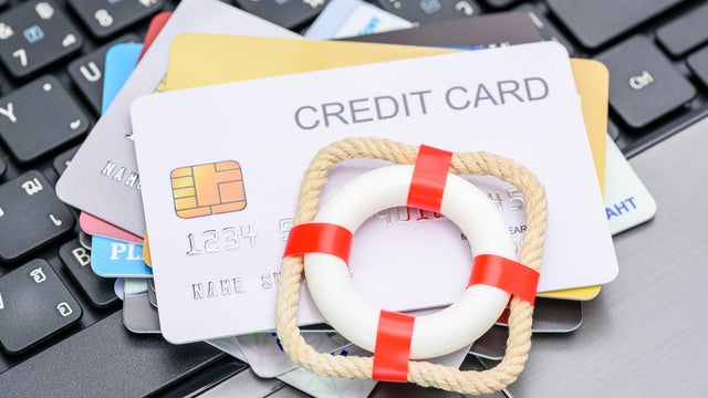 Household and credit card debt, personal loan, payment overdue, financial problems : Red lifebuoy or lifebelt atop a stack of credit cards on a laptop, depicting problems in repaying credit card debt. 