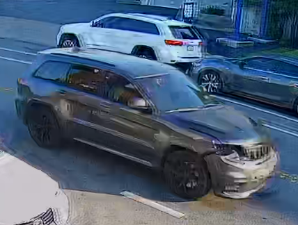 A dark-colored Jeep Grand Cherokee that has some damage in the front passenger side 