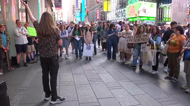 Crowd circling around a man with a microphone in Times Square 
