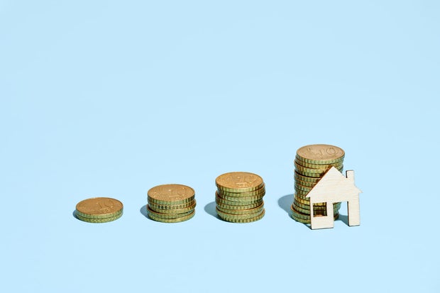 Wooden House Resting On A Stack Of European Union Coins Simulating A Growing Bar Graph
