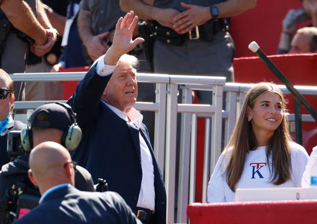 President Trump waves to the crowd on the first tee as his granddaughter Kai Madison Trump looks on at the Ryder Cup at Bethpage Black Golf Course in Farmingdale, New York, Sept. 26, 2025. 
