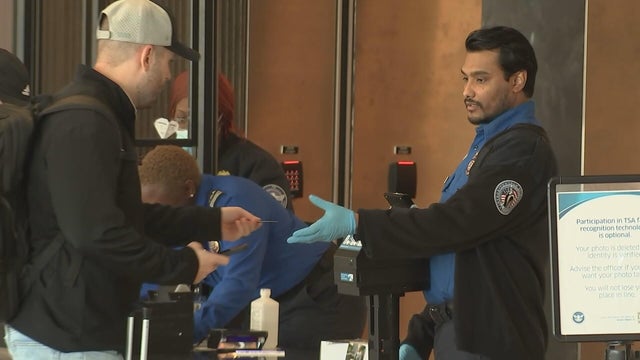 A TSA agent reaches out to take something from a traveler during the shutdown 