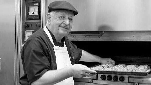 Vincent Termini Sr. pulls a rack of pastries out of an oven 