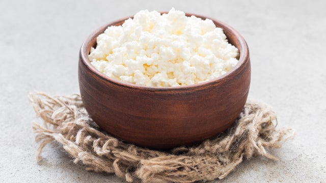 Freshly made cottage cheese in a clay bowl. On a linen napkin. Rustic style. Close-up 