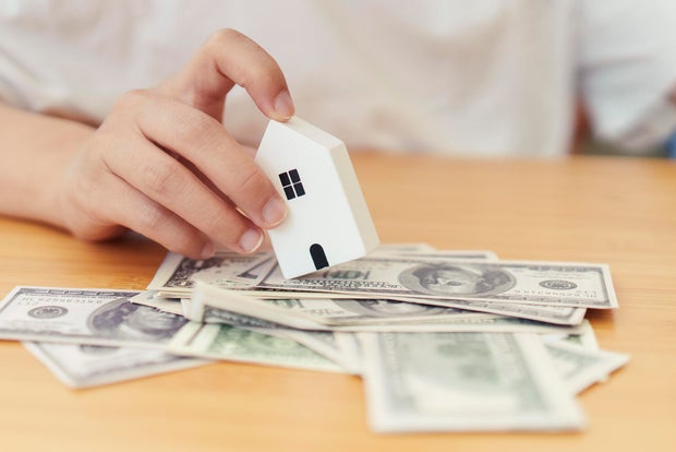 Real estate concept with a hand holding a small house, a family, and copyspace