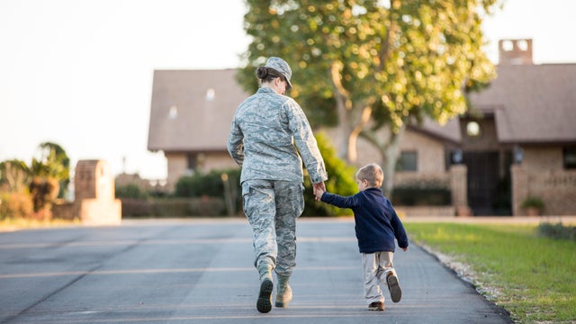 Rear view of female soldier walking with son at military air force base 