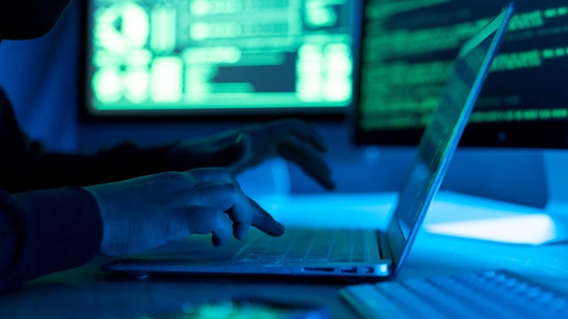 Hacker using laptop. Lots of digits on the computer screen. 