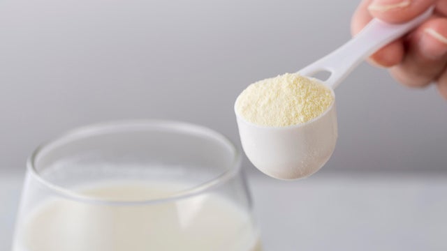 Glass of milk with powdered milk and spoon 