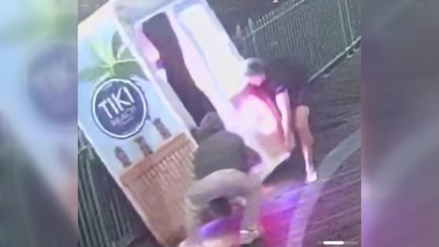 Two men trying to lift a photo booth over a boardwalk fence 