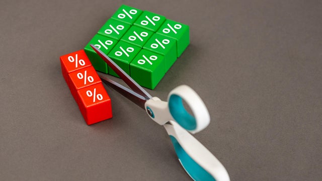Interest rate cuts. Reducing interest rates. Business concept. Scissors cutting the symbol of interest rates, copy space, grey background 