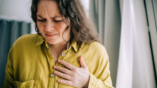 Woman suffering from chest pain holding hand over heart 