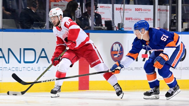 Alex Debrincat #93 of the Detroit Red Wings plays the puck against Emil Heineman #51 of the New York Islanders at UBS Arena on October 23, 2025 in Elmont, New York. 