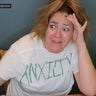 Woman wearing a t-shirt reading "anxiety" looking anxious 