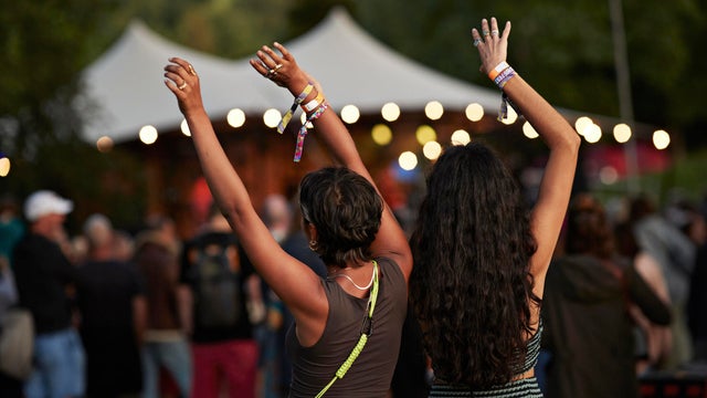 Multiracial female friends dancing with arms raised 