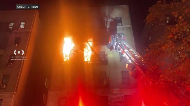 Flames shooting out of two windows in apartment building. 
