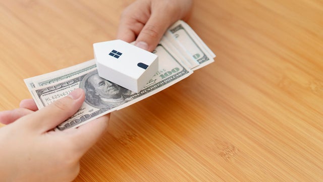 Two hand exchange money cash with small house Home loan and real estate concept 