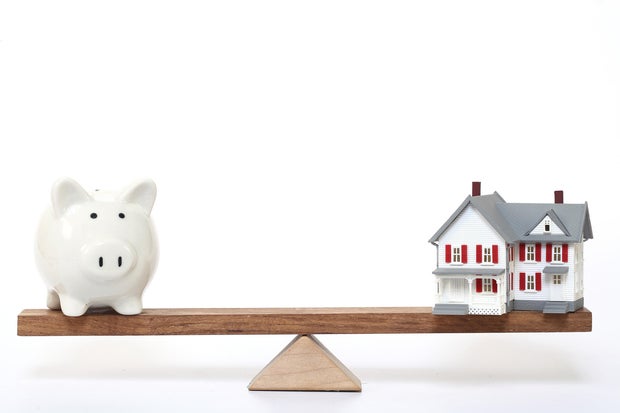 Model house and piggy bank on seesaw - Concept of Investment in real estate 