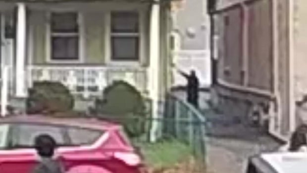 Man with his arms outstretched standing beneath a window