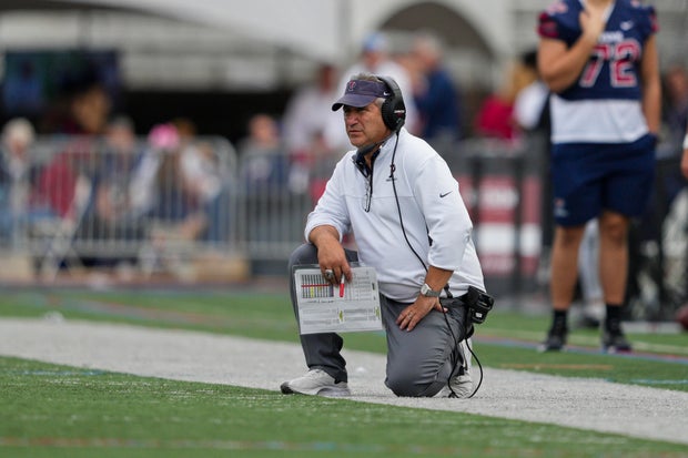 Pennsylvania Quakers head coach Ray Priore looks on during the game between the Pennsylvania Quakers and the Brown Bears on October 30, 2021 at Franklin Field, he's on one knee and wearing a headset
