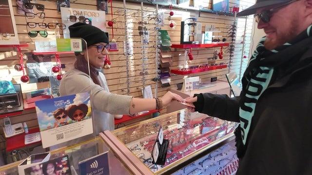 Shop employees hands a customer a card 