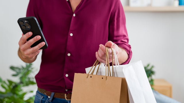 Man holding shopping bags and checking smartphone for black friday deals 