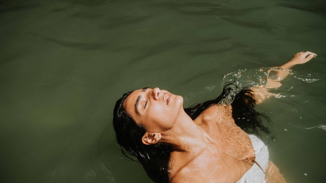 A beautiful Indian woman in  a white bikini immersed in the ocean 