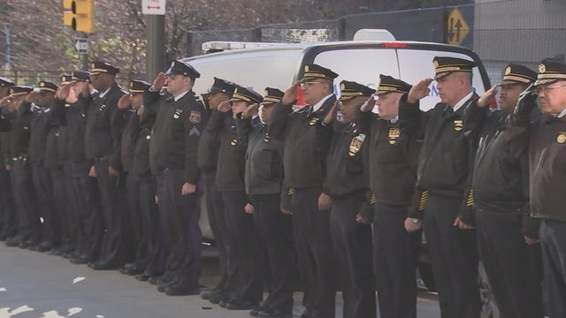 Officers stand in a line, saluting, during the procession 