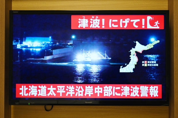 A tsunami warning is issued as live footage shows a boat leaving a port on a television in Sapporo, in Japan's northern Hokkaido prefecture, Dec. 8, 2025.