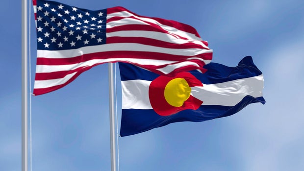 Colorado and US flags waving in the wind on a clear day