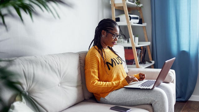 A young woman is working at a laptop at home 