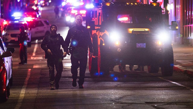 Close Up Shot Focused on Yellow Tape Showing Text Police Line Do Not Cross. Restricted Area of a Crime Scene. Bokeh Background with Flickering Siren Lights. Forensics Team Working on a Case 