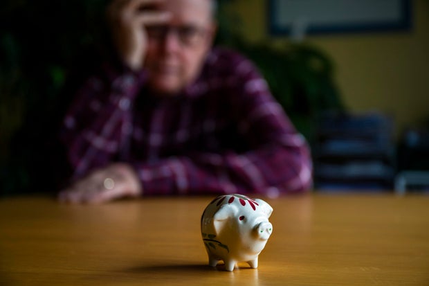 Retirement - Worried senior male looking at a tiny piggy bank