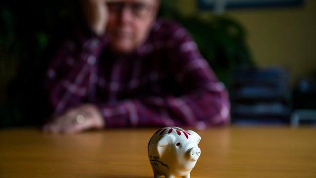 Retirement - Worried senior male looking at a tiny piggy bank 