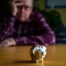 Retirement - Worried senior male looking at a tiny piggy bank 