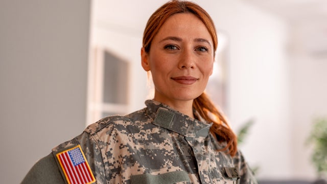 Portrait of female U.S. soldier in uniform with young daughter in front of home 