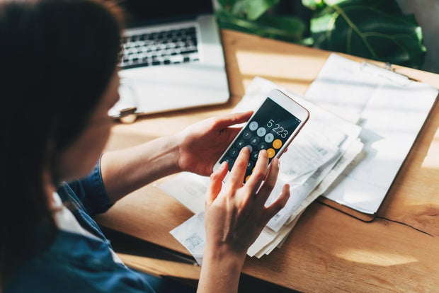 Woman accountant use calculator and computer with holding pen on 