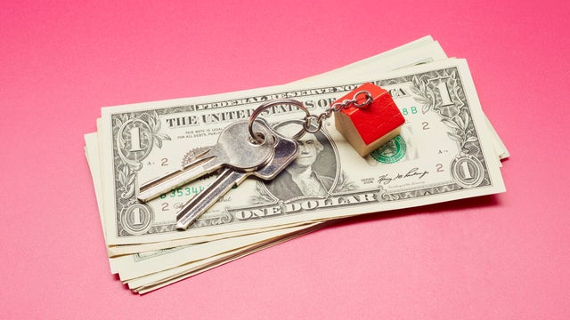 High angle view of keyring with a small house and American Dollar banknotes on colored background 