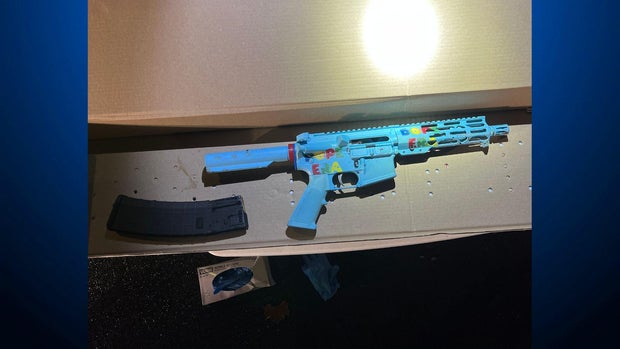 A powder-blue colored rifle with a decal that reads "Dope Era" next to a detachable magazine 